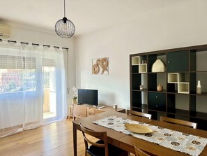 Ein Essbereich mit Holztisch, Stühlen, einem Fernseher und einem Bücherregal.