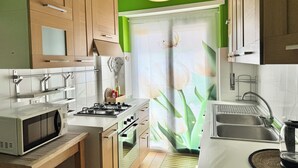 Une cuisine moderne avec des meubles en bois, une cuisinière à gaz, un four à micro-ondes, un évier et un luminaire suspendu.