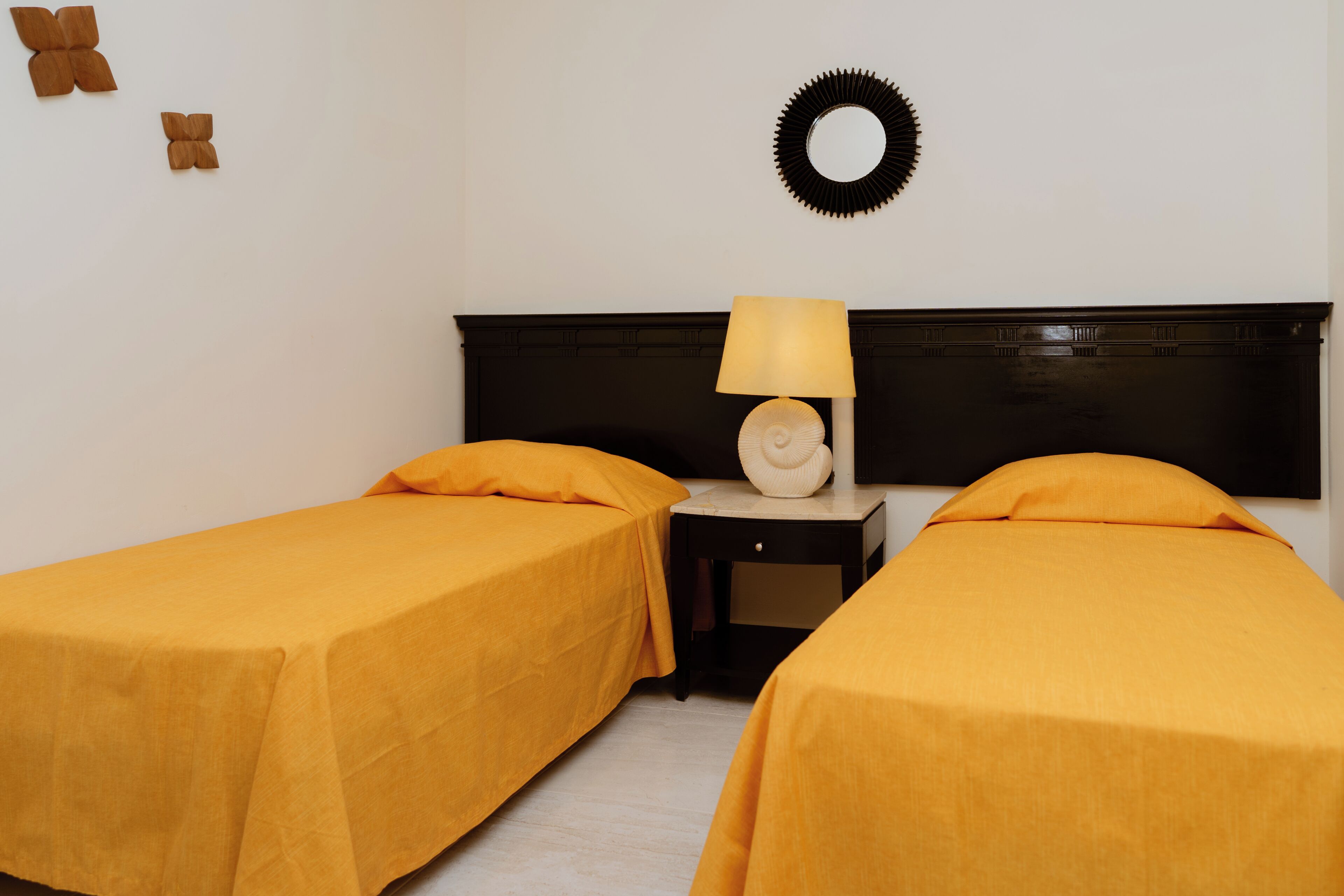 Una habitación con dos camas, una mesita de noche, una lámpara y un adorno en la pared.
