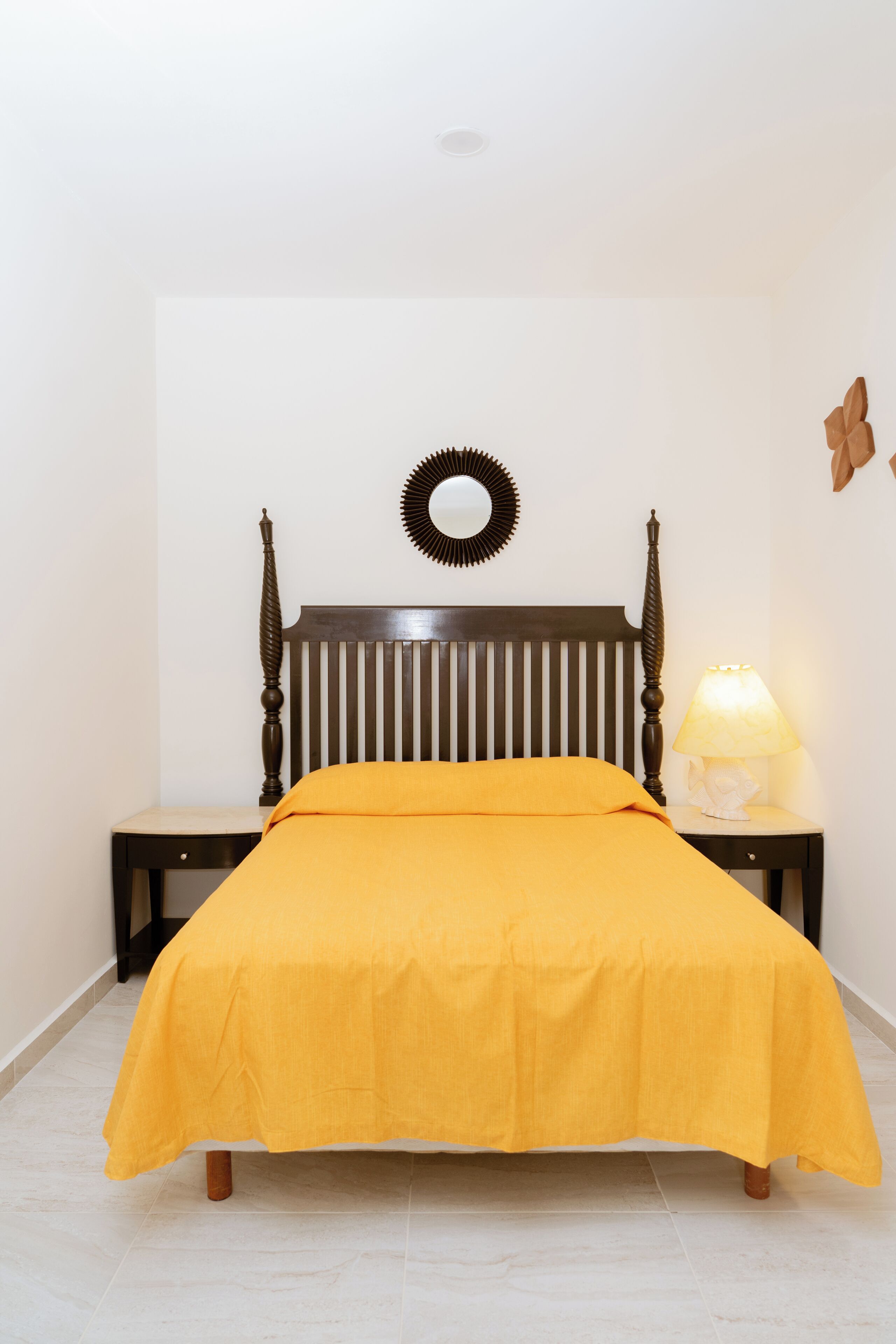 A bed with a headboard, a bedside table with a lamp, and a wall decoration.