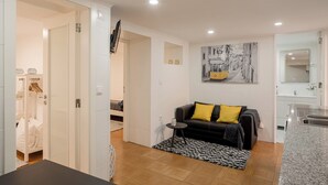 Ein modernes Wohnzimmer mit einer schwarzen Couch, einem kleinen runden Tisch und einem Bild an der Wand.
