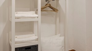 Ein weißer Kleiderschrank mit Regalen, einer Kleiderstange und einem Korb.
