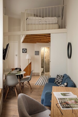 A compact, multi-level room with a bunk bed, a dining area, and a seating area. - Arroios Urban Studio with Mezzanine (Lisbon)