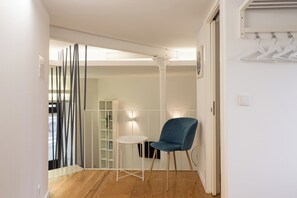 Habitació amb sòl de fusta, taula blanca, cadira blava, armari blanc i prestatgeria blanca.