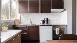 Una cocina moderna con armarios de madera oscura, encimera blanca, lavavajillas integrado y ventana que proporciona luz natural.