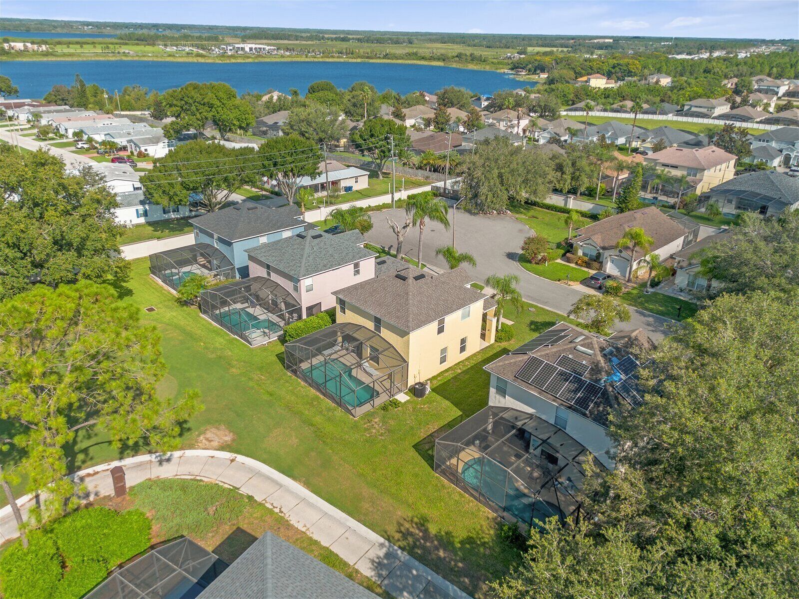 A residential area with houses, a swimming pool, and a lake in the background.