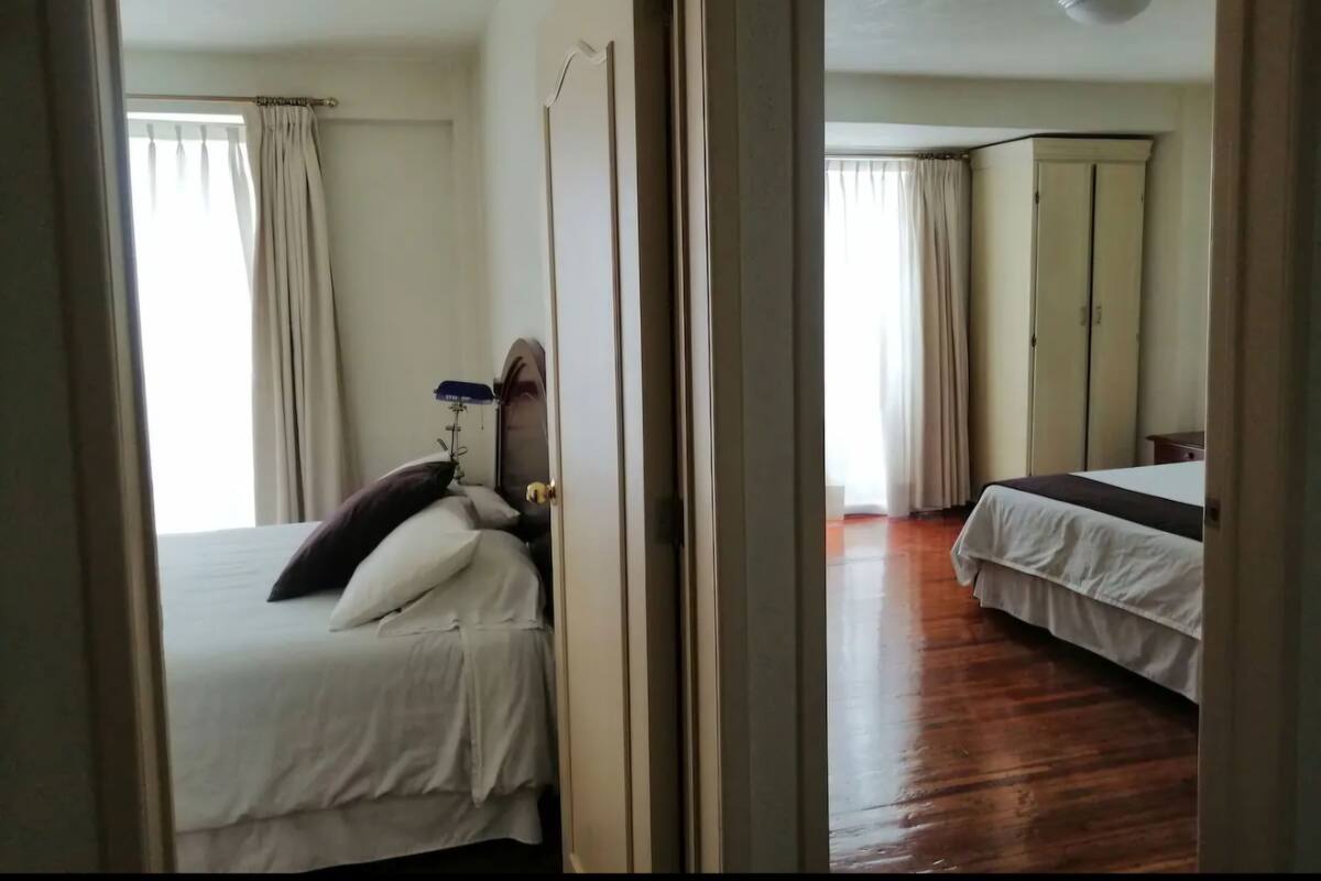 A bedroom with a bed, a bedside table, a lamp, and a wardrobe.