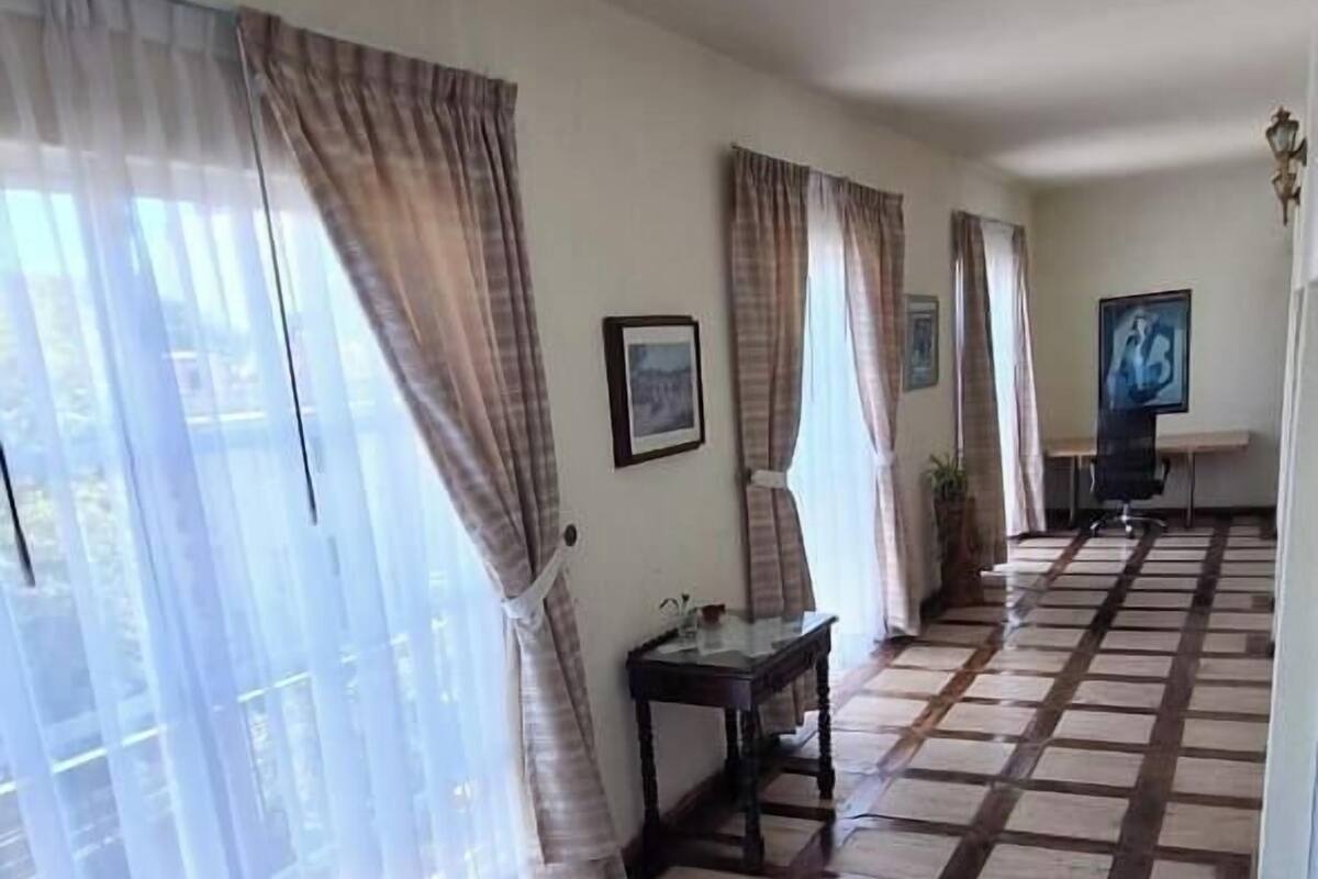 A room with a checkered wooden floor, a table with chairs, and a painting on the wall.