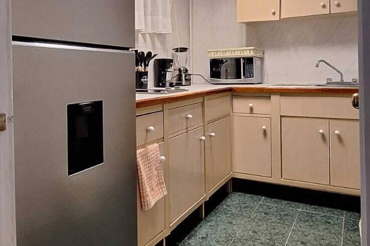 A kitchen with a refrigerator, microwave, and cabinets.