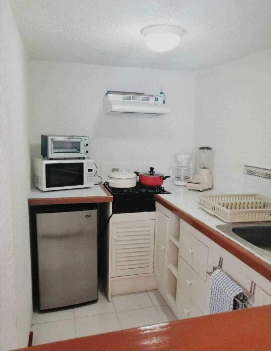 Una cucina compatta con forno a microonde, piano cottura e frigorifero.