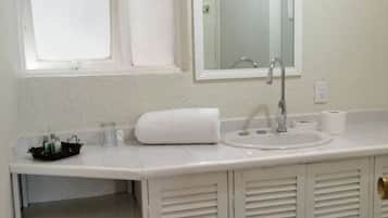 A bathroom with a white sink, mirror, and a shelf with toiletries.