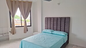 A bedroom with a bed, curtains, a headboard, and a window.