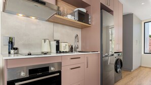 Une cuisine moderne équipée d’appareils électroménagers en acier inoxydable, d’un four encastré et d’un lave-linge.