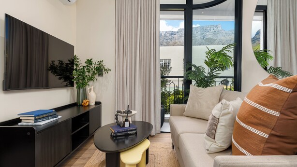 Un salon moderne doté d’un téléviseur à écran plat, d’un canapé, d’une table basse et offrant une vue sur une montagne.