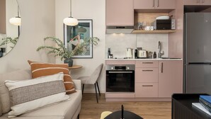 Une cuisine moderne avec des armoires roses, un four encastré et un réfrigérateur.