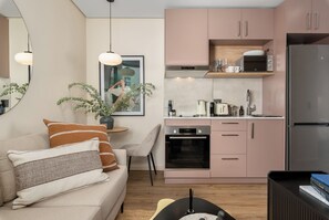 A modern kitchen with pink cabinets, a built-in oven, and a refrigerator. - Designer Apartment in Vredehoek | Mountain Views (Cape Town)