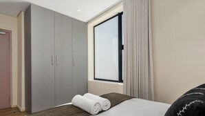 Une chambre d’hôtel avec un lit, une grande armoire, une fenêtre avec des rideaux et une vue sur l’extérieur.