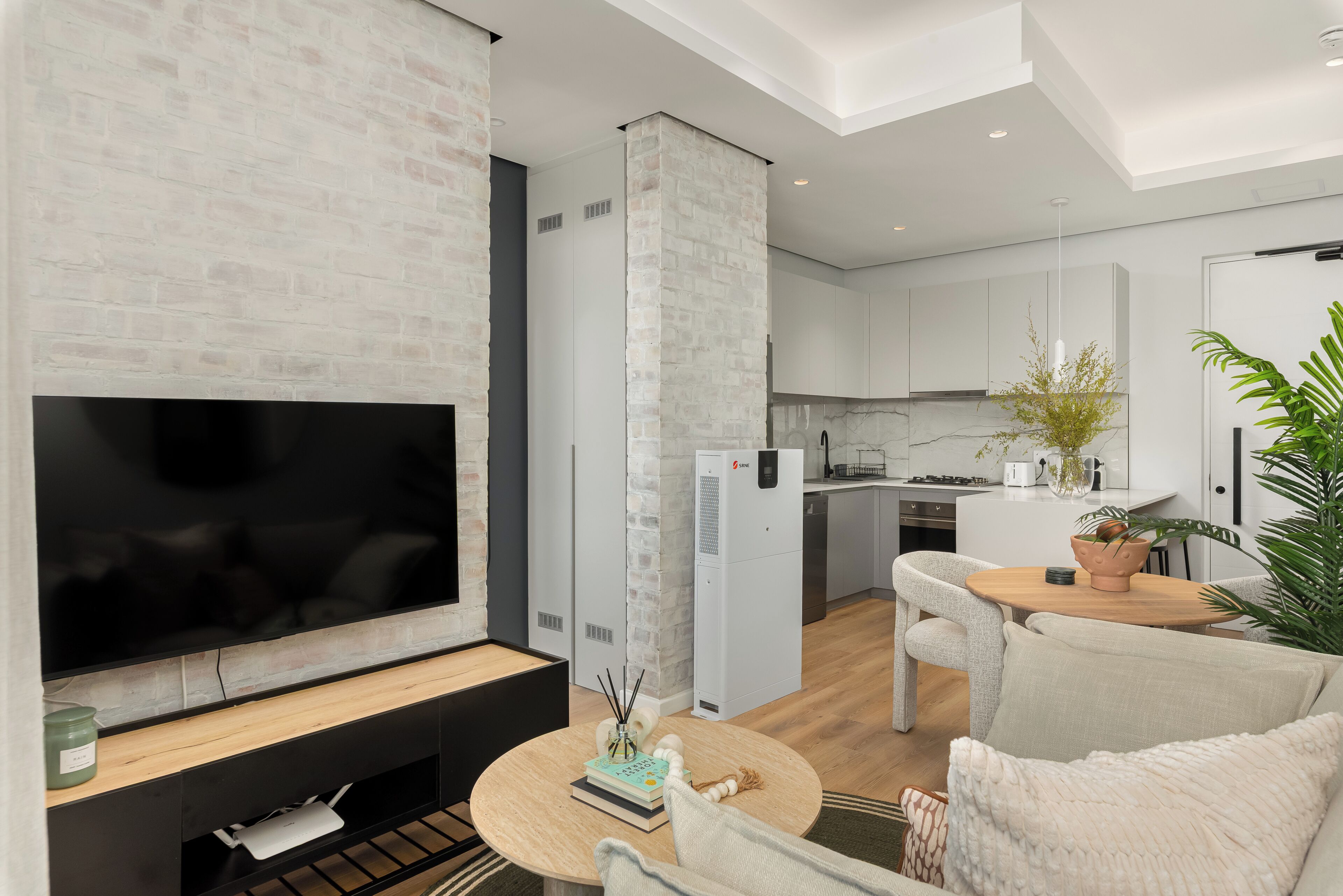 A modern living room with a flat-screen TV, a coffee table, and a sofa.