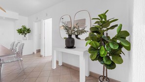 A modern dining area with a white table and chairs, a white bench, and potted plants.