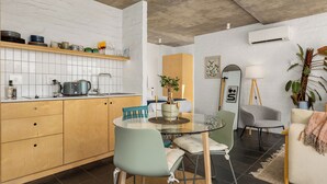 A modern kitchen with a dining area, white brick walls, and a large window. - Sunny Sea Point Stay with Balcony and Views (Cape Town)