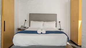 A neatly made bed with white linens, two bedside lamps, and a blue throw blanket. - Sunny Sea Point Stay with Balcony and Views (Cape Town)