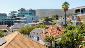 A residential area with modern buildings, a hillside, and a palm tree. - Sunny Sea Point Stay with Balcony and Views (Cape Town)