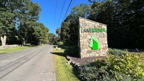 Carretera que conduce a un letrero con el nombre 'LAKERIDGE' y un símbolo de flecha verde.