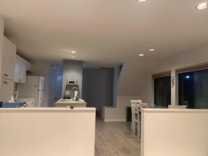 A compact kitchen with white cabinets, a built-in sink, and a dining area with a table and chairs. - Lakeridge Family Retreat 3-bedroom Townhouse (Torrington)