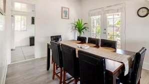 A dining area with a wooden table, black chairs, a potted plant, and a clock on the wall. - Guest Favorite Spacious Home w/ huge Yard, Sleeps 15, Near Dining & Attractions (Rialto)