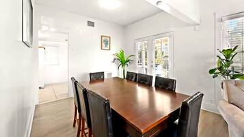 Une salle de conférence avec une table en bois et des chaises noires, des murs blancs et une plante en pot.