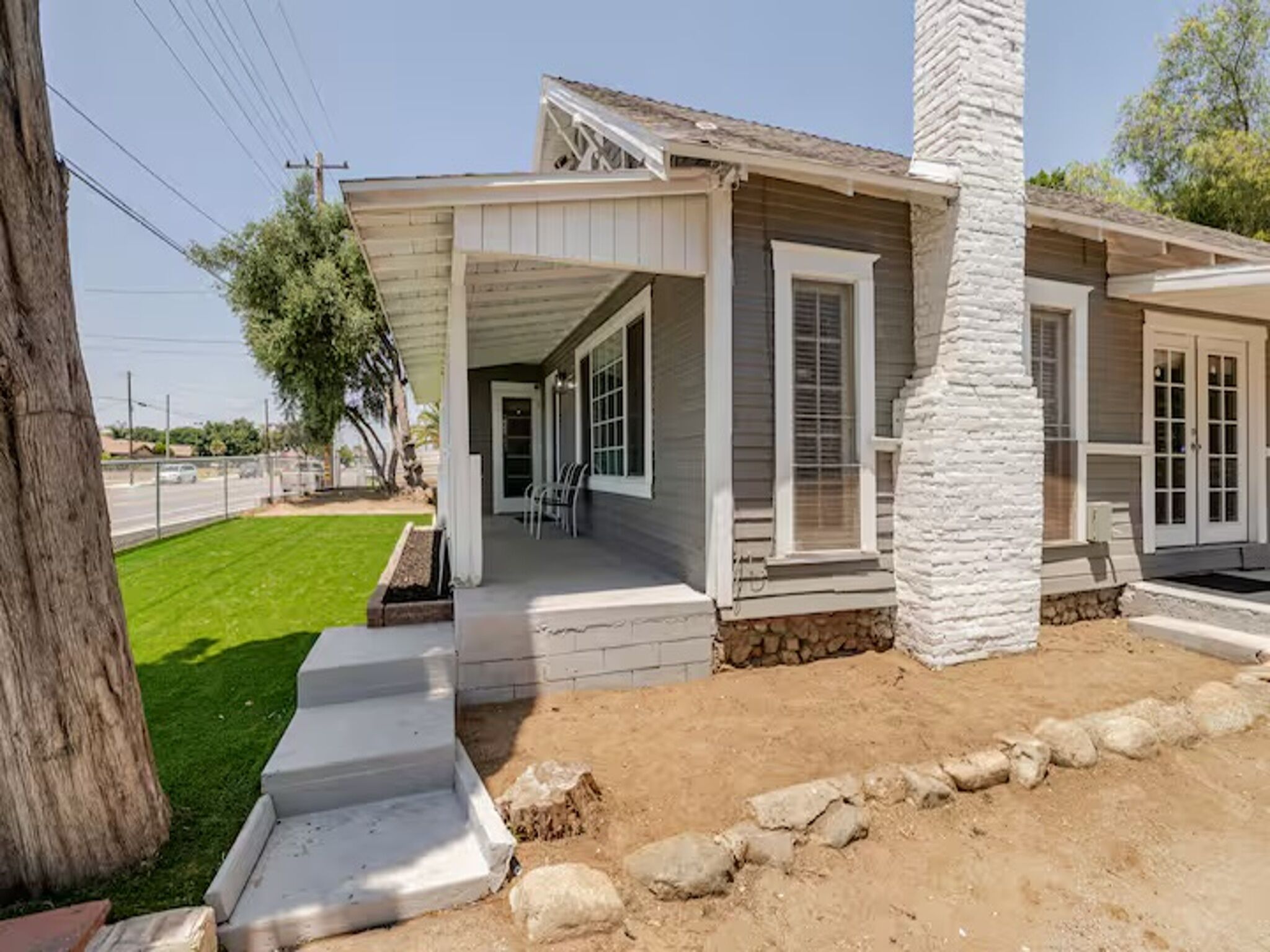 A house with a covered porch, a stone pillar, and a well-maintained lawn.