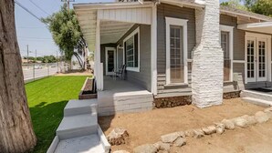 A house with a covered porch, a stone pillar, and a well-maintained lawn. - Guest Favorite Spacious Home w/ huge Yard, Sleeps 15, Near Dining & Attractions (Rialto)