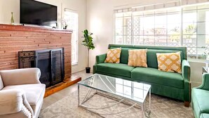 Un salon avec une cheminée, un canapé vert et une table basse en verre.