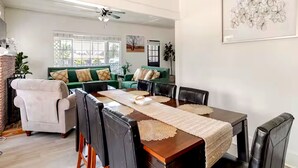 Un espace repas avec une table en bois, des chaises noires et un canapé vert en arrière-plan.