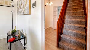 A staircase with carpeted steps and a wooden handrail, leading to a room with a white door and a hanging light fixture. - Guest Favorite Spacious Home w/ huge Yard, Sleeps 15, Near Dining & Attractions (Rialto)