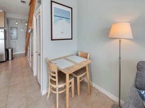 A dining area with a table and chairs, a lamp, and a framed picture on the wall. - Southern Sunshine, Beachfront Living — Fully Updated & Steps to the Sand (Navarre Beach)