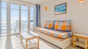 Une pièce comprenant un canapé, une table, une chaise et donnant sur l’extérieur par une porte coulissante.