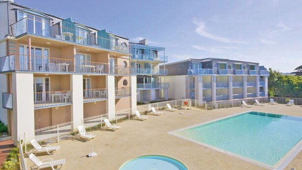 Um hotel com piscina, várias varandas e espreguiçadeiras.