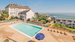 A hotel with a swimming pool, lounge chairs, and a view of the ocean. - Cosy T2 avec vue sur la ver | La plage à proximité (Audierne)