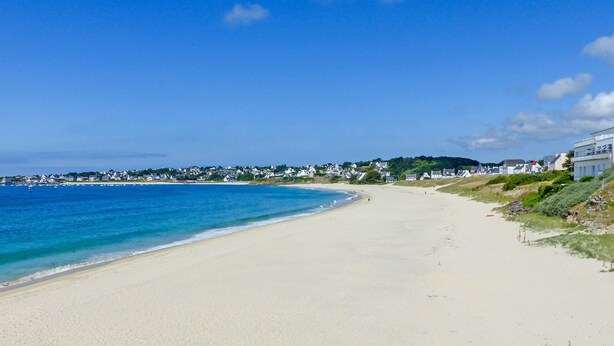 A beach with a clear blue sky, sandy shore, and houses along the coastline. - Cosy T2 avec vue sur la ver | La plage à proximité (Audierne)