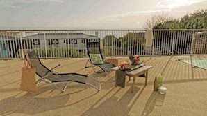 A rooftop terrace with two lounge chairs, a table with a fruit basket, and a view of buildings in the background. - Cosy T2 avec vue sur la ver | La plage à proximité (Audierne)