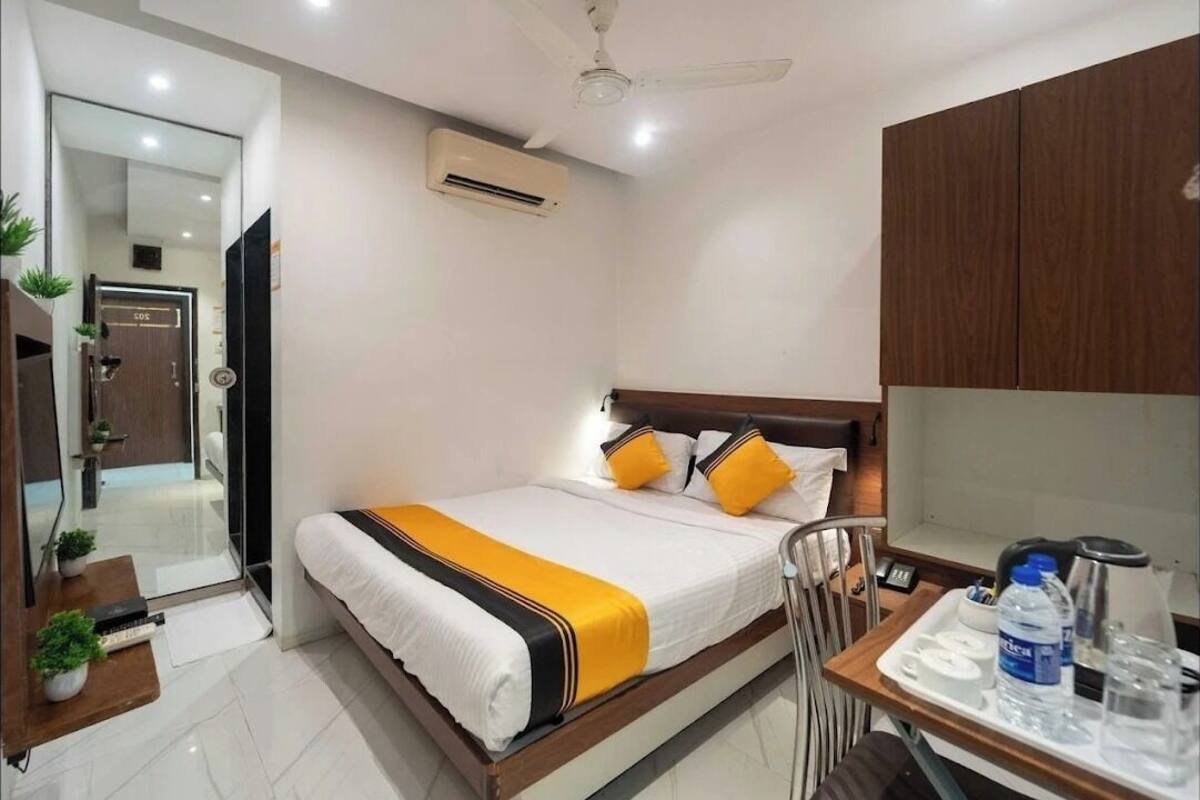 A hotel room with a bed, bedside table, chair, desk, and a mirror.