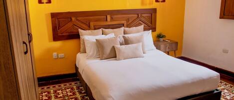 Una cama con cabecera de madera, un tapete estampado y dos lámparas colgantes.