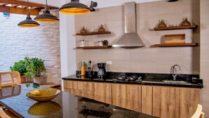 Een keuken met houten kastjes, een granieten aanrechtblad, hangende hanglampen en een spatwand.