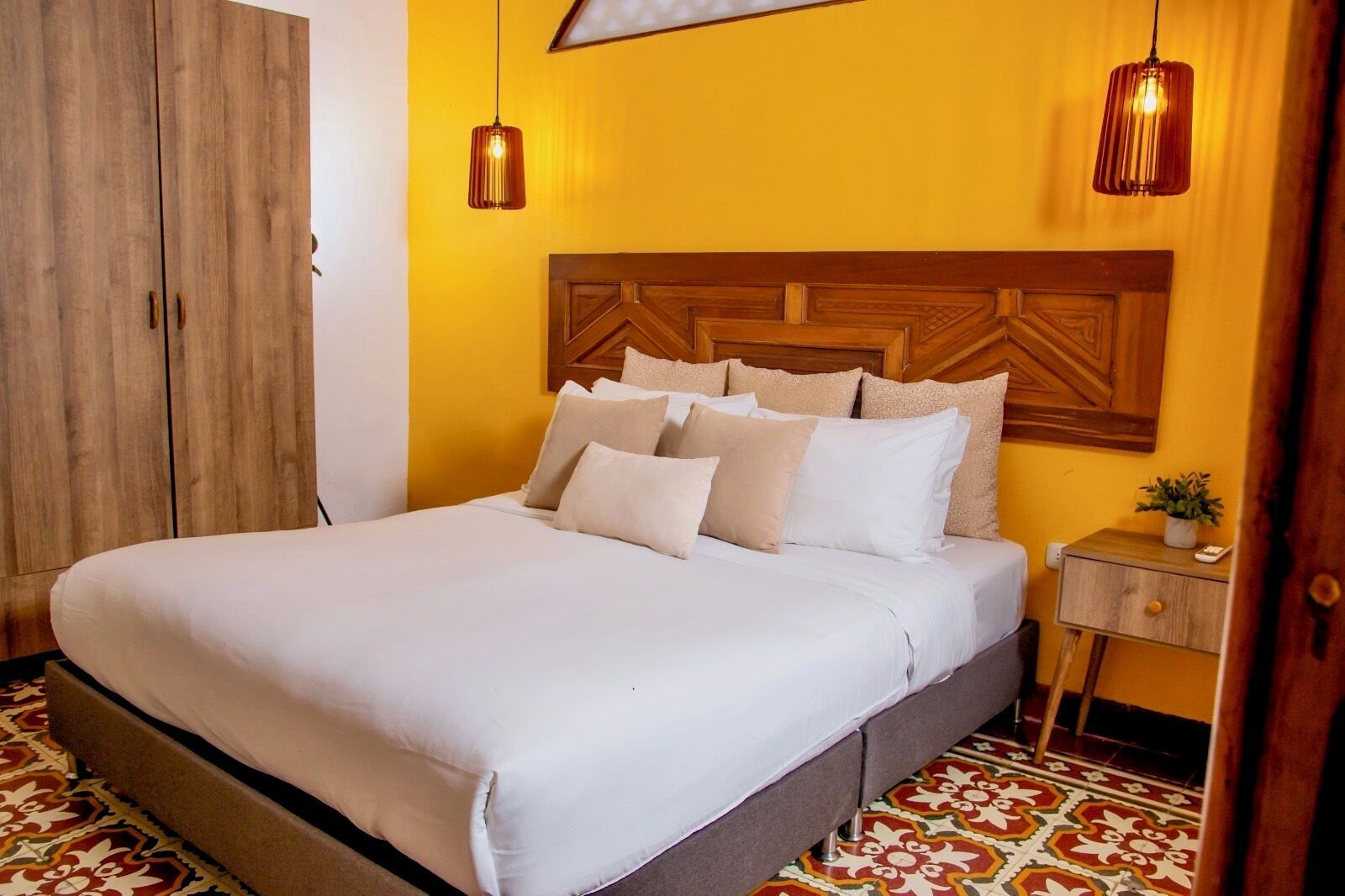 A bedroom with a bed, bedside table, lamp, and wardrobe.