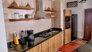 Een keuken met houten kastjes, een zwart aanrecht, een roestvrijstalen afzuigkap en een koelkast.