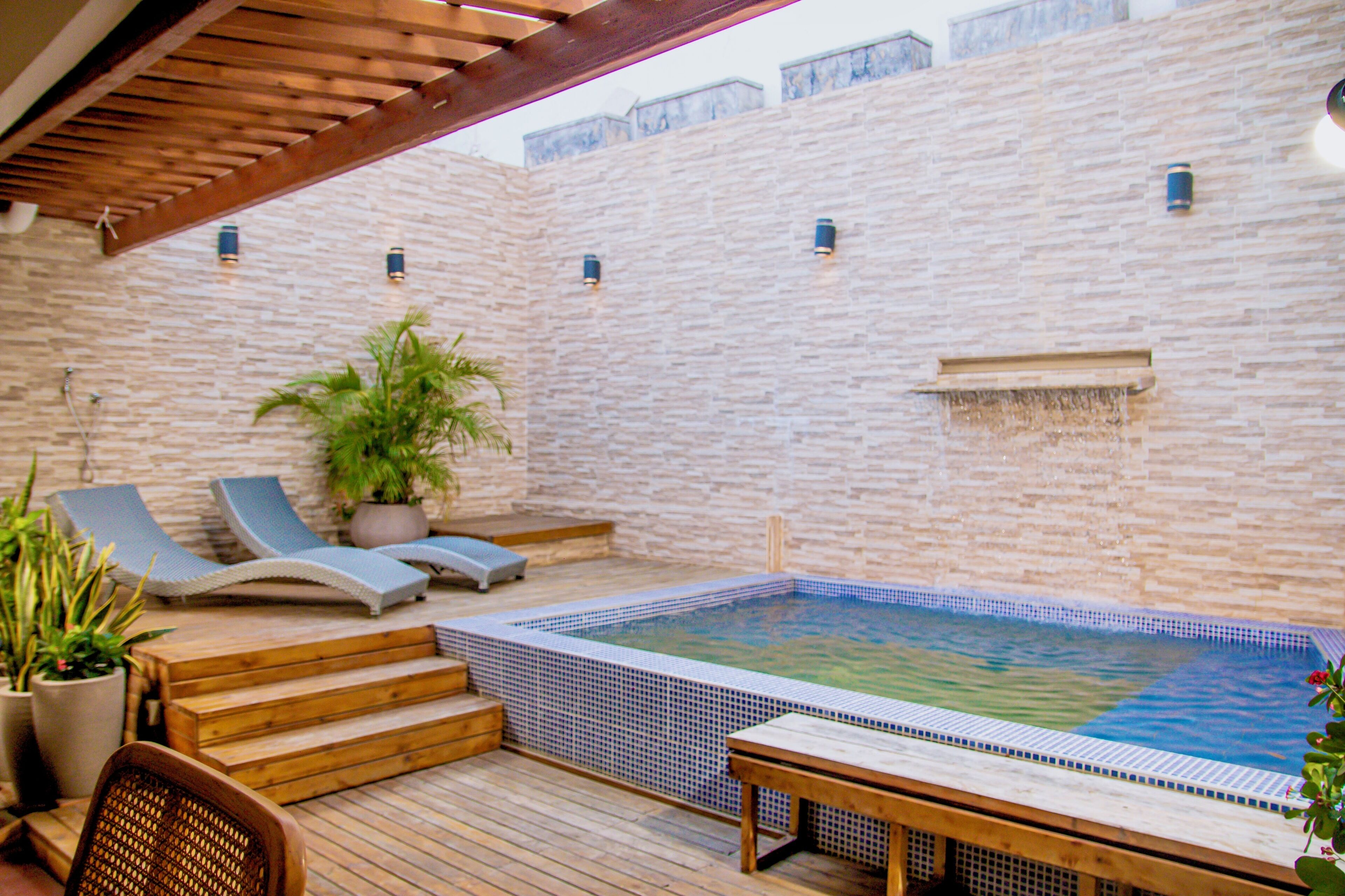 Un espace piscine aménagé sur le toit, avec des chaises longues, un jacuzzi et une terrasse en bois.