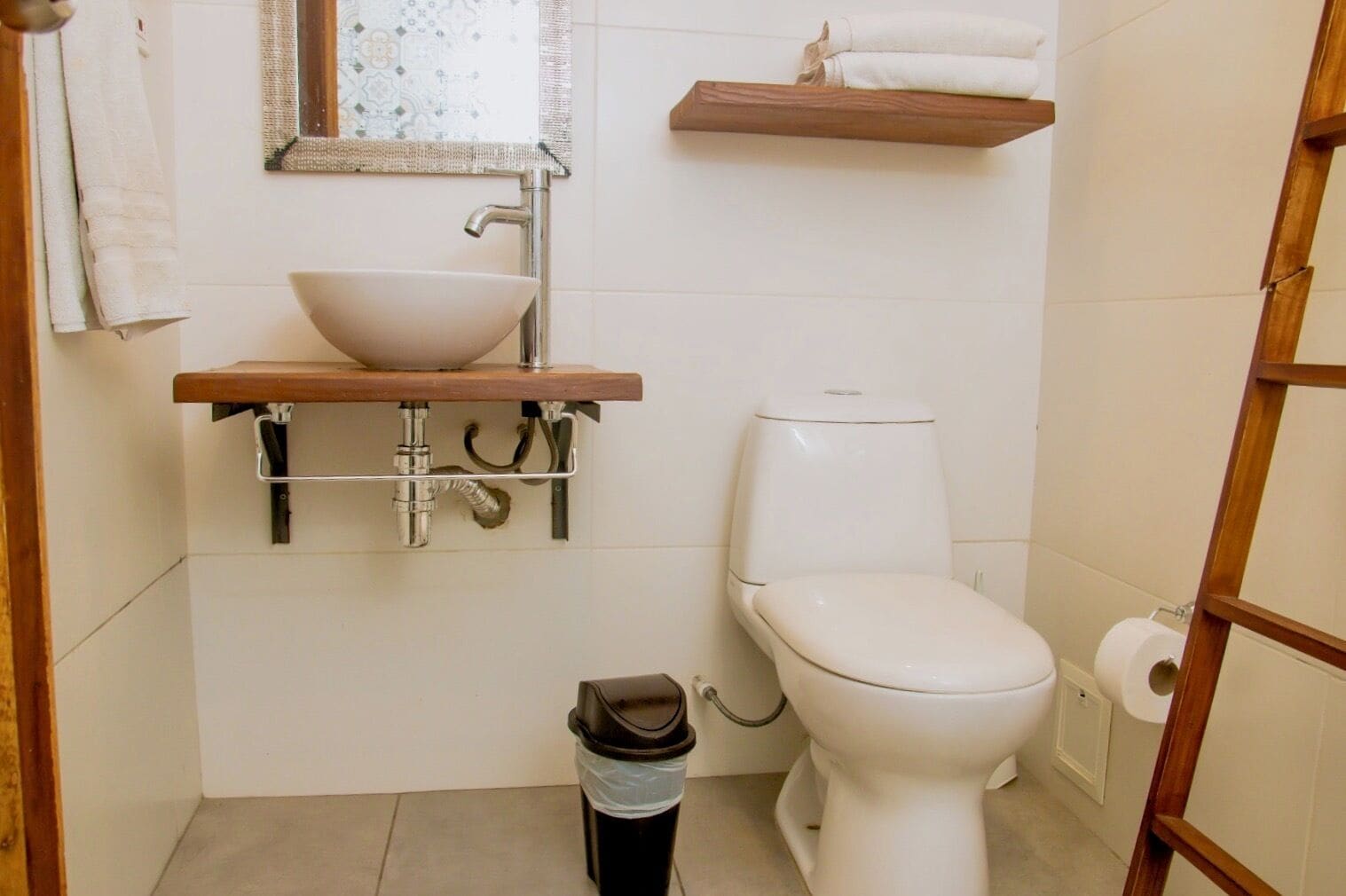 A bathroom with a white sink, toilet, and trash bin.