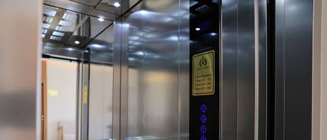 An elevator interior with a digital display panel indicating floor levels and a reception sign.