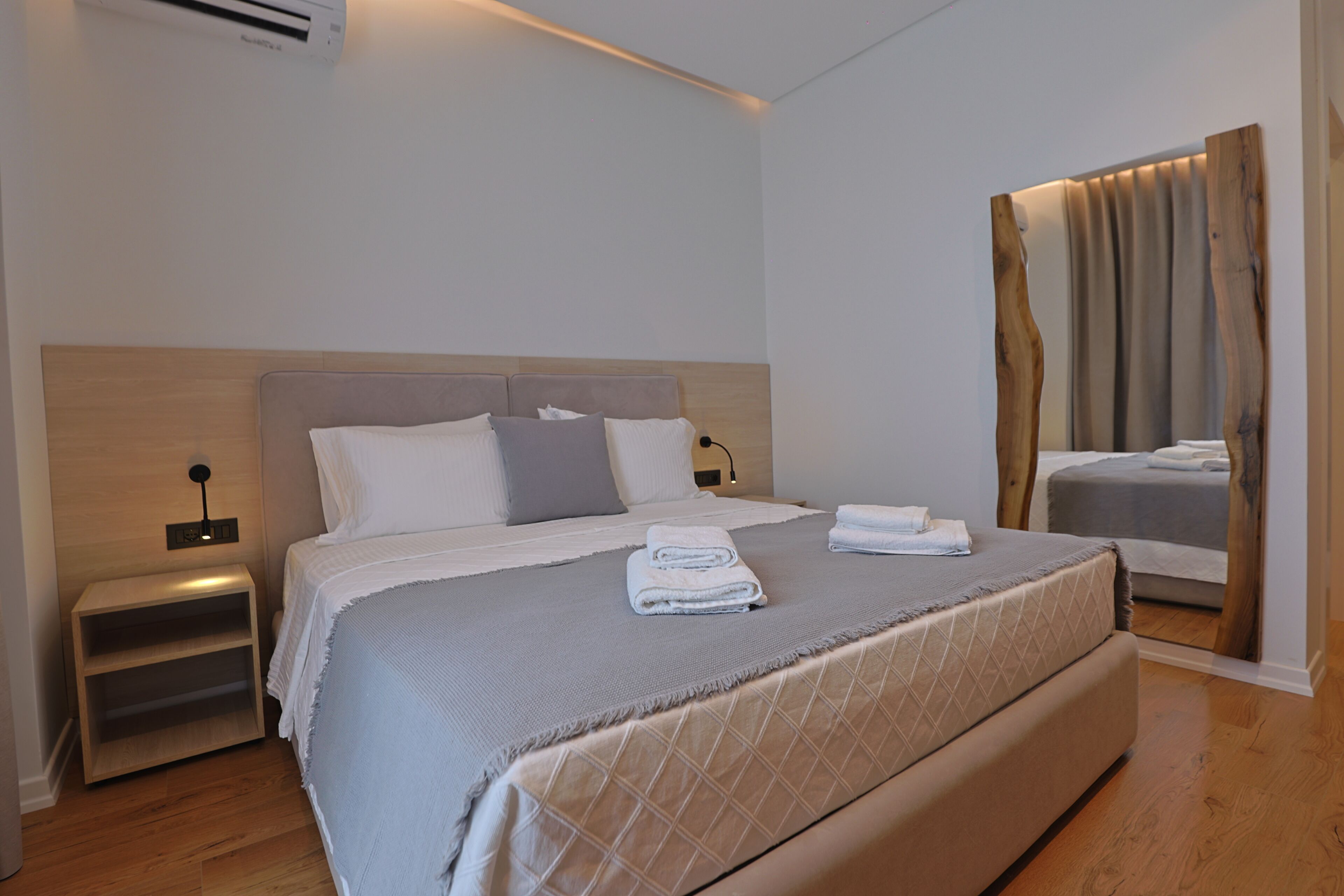 Ein modernes Hotelzimmer mit einem großen Bett, einem Nachttisch und einem Spiegel.